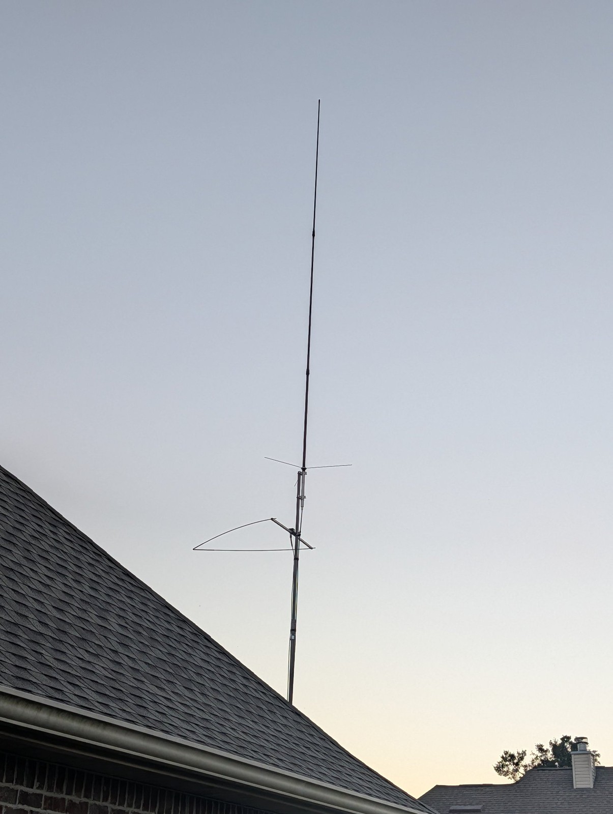 A GP-9 vertical antenna and 6m Omniangle antenna mounted above a rooftop against a dusk sky